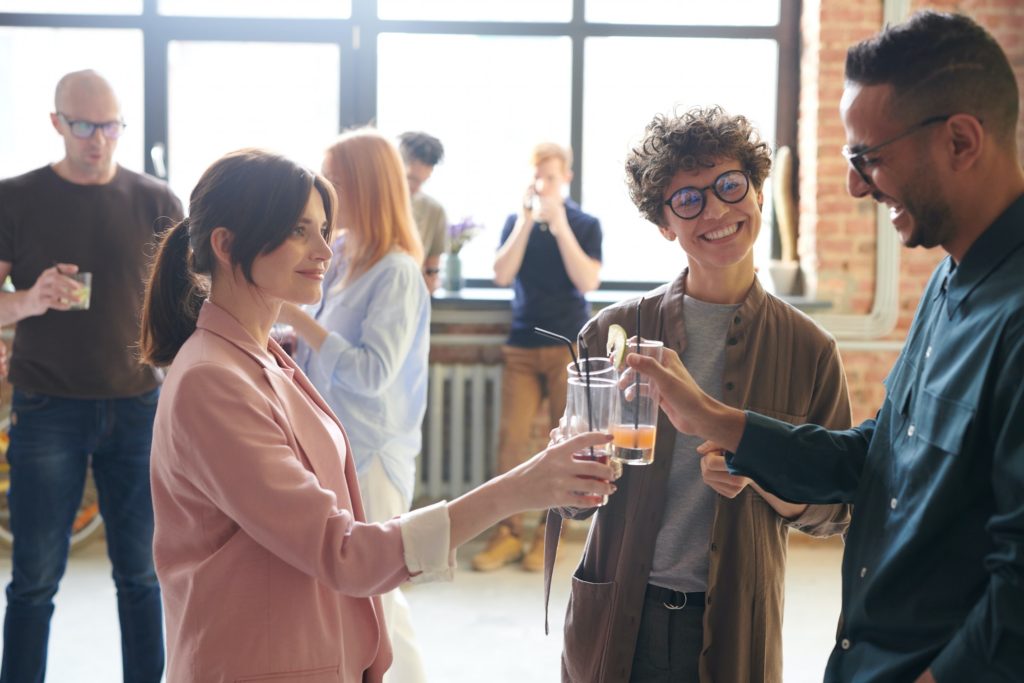 a group of people raising their drinks and talking - casual conversation starters