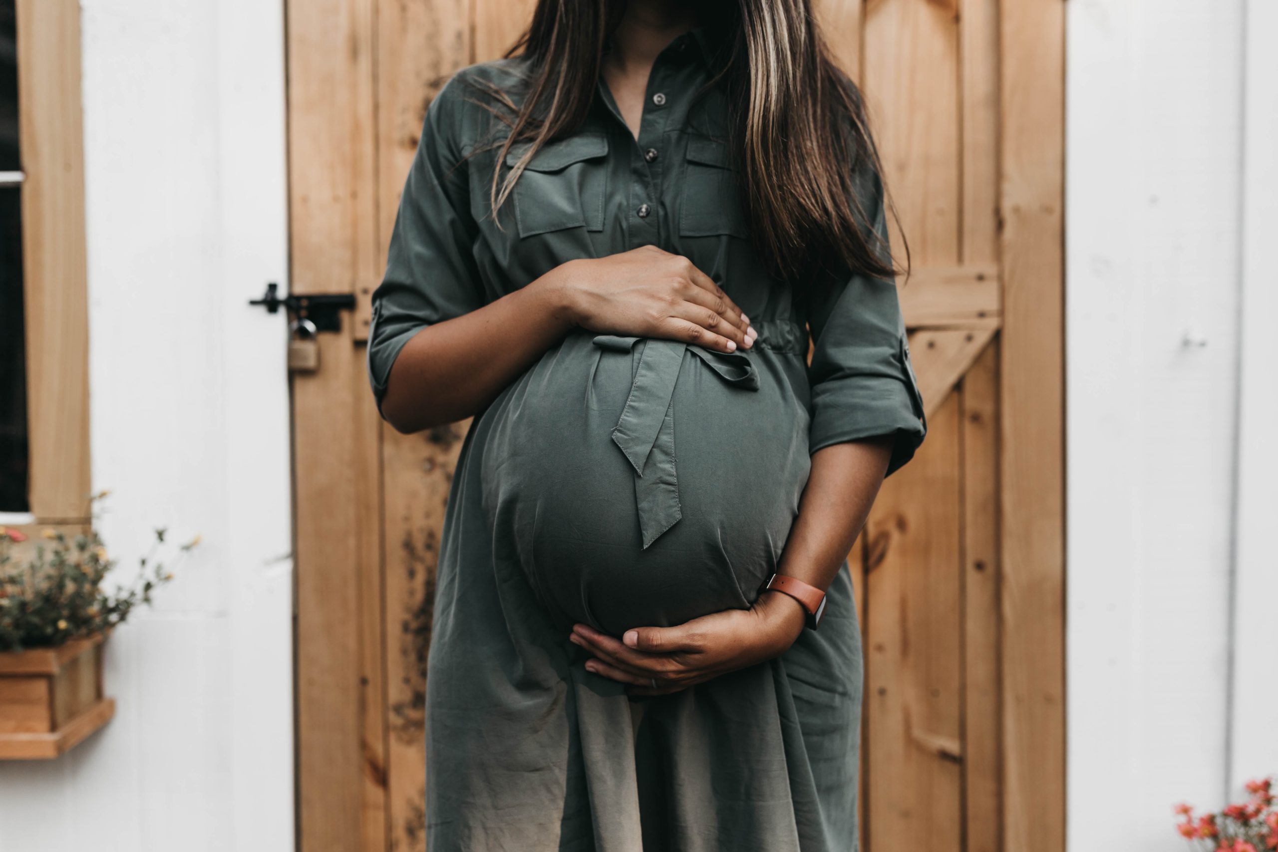 pregnant woman holding her stomach in a green silk dress