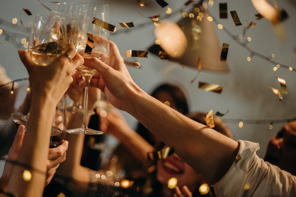 a group of people raising their glasses in gold confetti