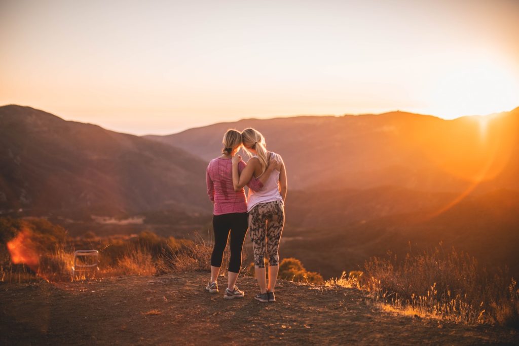 two friends hugging at sunset